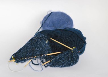 Örgü iğneli fotoğraf, iplik yumakları ve sağlam beyaz bir arkaplanda örülmüş bir ceket, el sanatları.