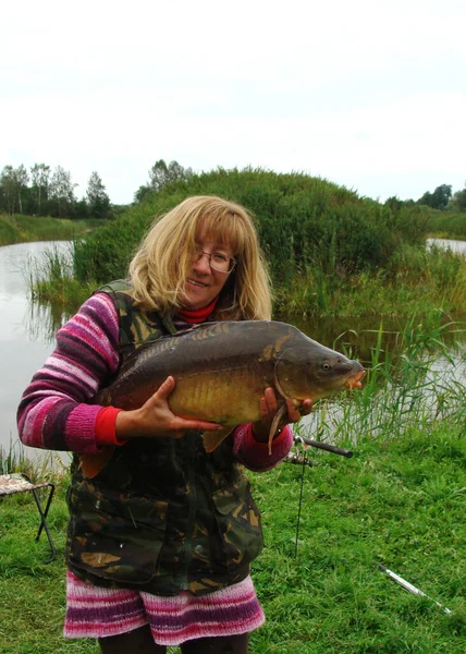 happy woman with big carp, carp fishing, spending free time fishing, summer