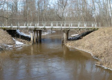 Beton köprülü manzara, ilkbaharın başlarında, çıplak ağaçlar, yerde kar planı, Kuja nehri, Madona, Letonya