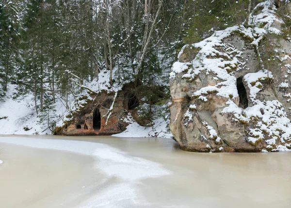 winter landscape with Anfabrikas rock Ligatne, artificial caves in the rock wall, all covered with snow, Ligatne, Latvia