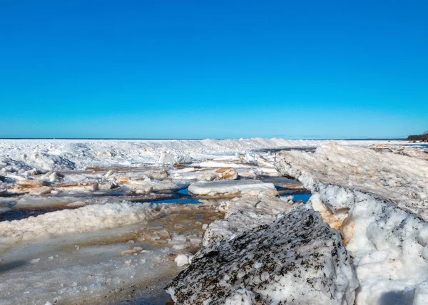 winter landscape by the sea, ice pieces of different sizes, sea horizon in the distance, blue sky, winter