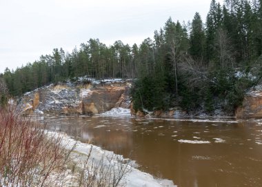 İlkbaharın başlarında nehir manzarası, kumtaşı çıkıntısı, suda buz küpleri, karşı kıyıdan nehir kıyısı, Erglu kayalıkları, Gauja nehri, Cesis, Letonya