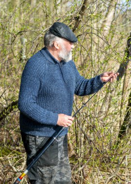 Bir balıkçıyla bahar manzarası, balıkçı oltaları denetliyor, göl kıyıları, doğada bahar.