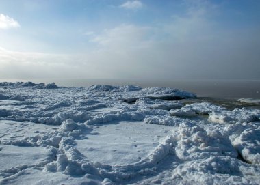 Deniz kenarındaki kış manzarası, karlı, deniz kıyısındaki ilginç buz şekilleri, beyaz bir kar tabakasıyla kaplı kumullar, kış