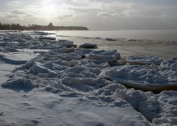 Deniz kenarındaki kış manzarası, deniz kenarındaki karlı buz parçaları ve denizdeki buz dokusu, beyaz kar tabakasıyla kaplı kum tepeleri.