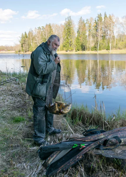 Wiosenny Krajobraz Jeziorem Rybak Pokazuje Złowioną Rybę Brzegu Jeziora Spokojną — Zdjęcie stockowe