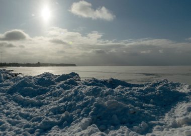 Deniz kenarındaki kış manzarası, deniz kenarındaki karlı buz parçaları, parlayan beyaz kar tabakasıyla kaplı kumullar, kış.