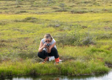 Güzel bataklık manzarası, mavi gökyüzü ve su, kadın bataklık manzarası, bataklıkta kar ayakkabılarıyla yürüyüş, geleneksel bataklık bitkileri, yosunlar ve ağaçlar, yazın bataklık.