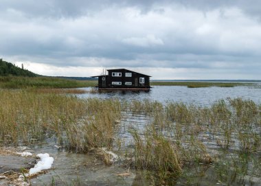 Sazlık gölü kıyısında ahşap bir kayıkhane manzarası.