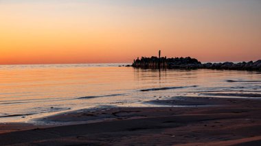 Deniz kenarında büyülü bir gün batımı, deniz kıyısında koşan mutlu bir köpek, güneşin son ışınları sakin deniz yüzeyine yansıyor, Tuja sahili, Vidzeme sahili, Letonya