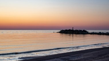 Deniz kenarında büyüleyici bir gün batımı, güneşin son ışınları sakin deniz yüzeyine yansıyor, parlak renkler, Vidzeme sahili, Letonya