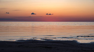Deniz kenarında büyüleyici bir gün batımı, güneşin son ışınları sakin deniz yüzeyine yansıyor, parlak renkler, Vidzeme sahili, Letonya