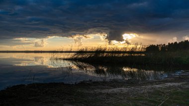 Göl kenarında harika bir gün batımı, sonbahar manzarası, güneş ışınları gölün sakin yüzeyi, Burtnieki Gölü, Letonya