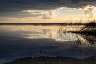 Göl kenarında harika bir gün batımı, sonbahar manzarası, güneş ışınları gölün sakin yüzeyi, Burtnieki Gölü, Letonya