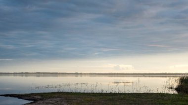 Göl kenarında harika bir gün batımı, sonbahar manzarası, göl yüzeyine yansıyan gökyüzü, suda güzel yansımalar, Burtnieki Gölü, Letonya