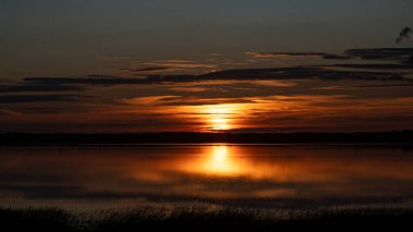 Göl kenarında harika bir gün batımı, sonbahar manzarası, güneş ışınları gölün sakin yüzeyi, Burtnieki Gölü, Letonya