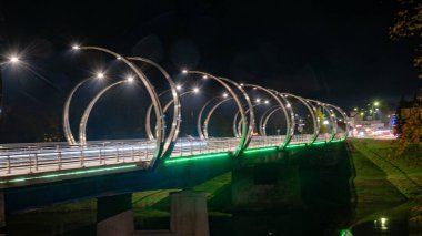 Renkli köprü ışıklandırmasıyla sonbahar manzarası, akşam alacakaranlığı, güzel, bulanık ışık nesneleri, Gauja, Valmiera, Letonya üzerindeki köprü