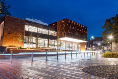 Güzel bir akşam manzarası, sonbaharda şehir manzarası aydınlanmış sokaklar ve evler, yansımalar ve parlak renkler, Valmiera, Letonya