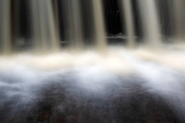 Küçük, hızlı bir nehrin, güzel su oluşumlarının, sonbahar manzaralarının, doğadaki kasımın, Ieriku değirmeninin, Melderupe 'nin, Letonya' daki sonbaharın görüntüsü.