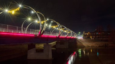 Şehir köprüsü şenlikli renklerle süslenmiş, parlak dekorasyonlar, gece manzarası, Valmiera, Letonya