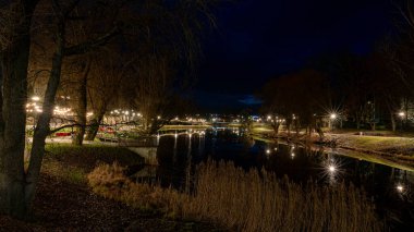 Noel havasında muhteşem dekore edilmiş şehir, çeşitli ışıklar ve dekorasyonlar, dekore edilmiş evler ve köknar ağaçları, gece manzarası, Valmiera, Letonya