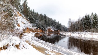 Nehir ve kumtaşı çıkıntılı kış manzarası, buzla donmuş nehir, ağaçlara düşen kar, Erglu kayalıkları, Cesis belediyesi, Letonya