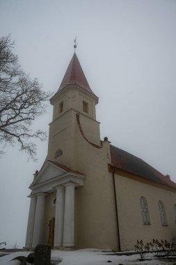 Bahar manzarası sabah sisli küçük bir kırsal kilise, nemli ve bulutlu hava, Rubene Kilisesi, Valmiera İlçesi, Letonya