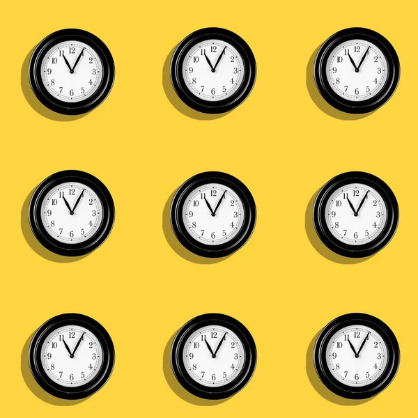 A Classic hand clocks pattern on yellow background. Time passing concept with clock pointing at 11 in the morning.