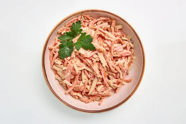 Peynirli haşlanmış sosis salatası ve beyaz soslu elma. Beyaz arka planda beyaz yuvarlak bir tabakta maydanozla süslenmiş..
