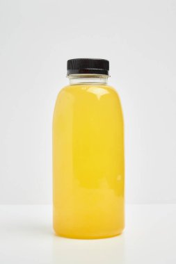 Transparent plastic bottle with a black lid, with sea buckthorn juice inside on a white background.