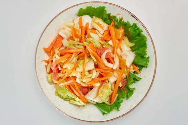 Taze Pekin lahanası salatası, havuç, domates, kereviz, baharatlı yeşil marul yaprağı ile beyaz arka planda yuvarlak beyaz bir tabakta.