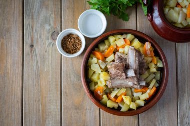 Kuzu kaburgalı fırında patates. Kuzu, patates ve sebzeli kil tabakta.