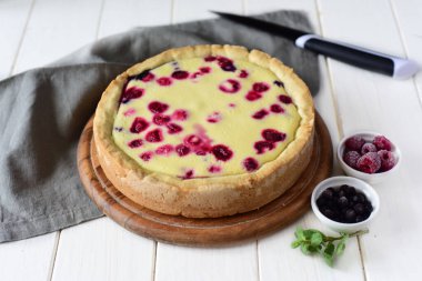 Beyaz bir masada meyveli turta. Yaban mersini ve ahududu turtası ahşap tabakta