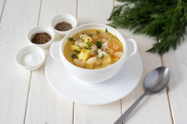 Lezzetli öğle yemeği: sebzeli sıcak tavuk çorbası ve beyaz arka planda beyaz tabakta makarna..