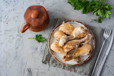 Sağlıklı bir atıştırmalık: Gri arka planda beyaz tabakta pişmiş tavuk bacağı. Üst görünüm