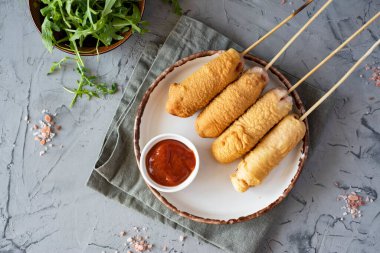 Sosisler hamur içinde çubukta beyaz bir tabakta gri bir arka planda.