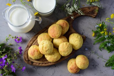 Lezzetli şekerli kurabiyeler, bir kupa süt ve gri arka planda bir sürahi süt..
