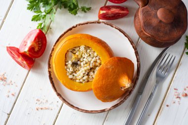 Sıcak bir öğle yemeği: İnci lapalı fırında balkabağı ve beyaz tabakta sebze. İnci lapasıyla doldurulmuş balkabağı. Üst görünüm.