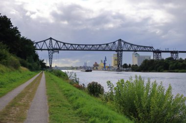 Almanya 'da Rendsburg - 22 Ağustos 2025: Kiel Kanalı' ndaki Rendsburg Yüksek Köprüsü 'nün altından geçen kargo gemisi