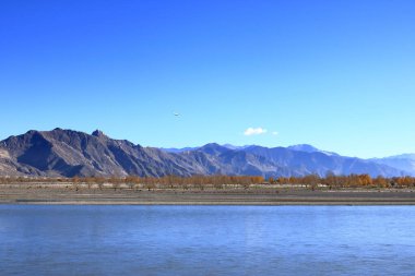 Yarlung Tsangpo nehri üzerinden Lhasa, Tibet, Çin 'e yaklaşan bir uçak, Brahmaputra' nın üst kısımlarında, yüksek dağlık arka planda.