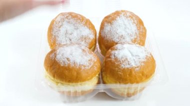 Kadın yavaşça plastik kutudan bir çörek çıkartıyor. Tatlı Pembe Kek. Kız plastik bir kutuyu mahvetti.