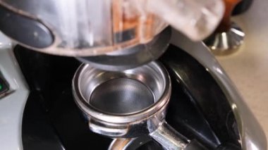 Kahve dükkanında sıcak içecek yapmak için öğütücü makine kullanan profesyonel bir barista çalışanı. Kahve makinesi. Kahve çekirdeklerini öğütüyorum. Modern bir kahve makinesinde kahve yapma süreci. Yakın plan..