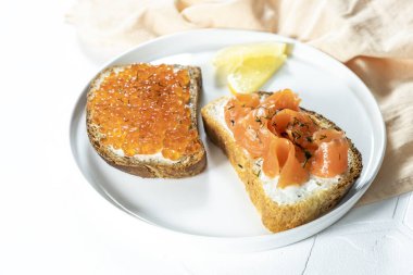 Beyaz zemin üzerinde kırmızı havyar olan dilimler. Kırmızı balık ve roka sandviçi, seçici odaklanma, kopyalama alanı. Üst görünüm. 