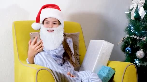 Kerstmis online gefeliciteerd. Glimlachend meisje die mobiele telefoon gebruikt voor videogesprekken. Pratende vrienden en ouders. — Stockvideo