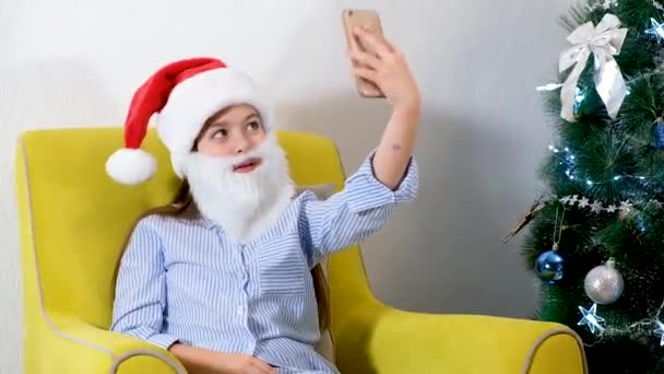 Parabéns online de Natal. Menina sorrindo usando telefone celular para chamada de vídeo. Criança falando amigos e pais. — Vídeo de Stock