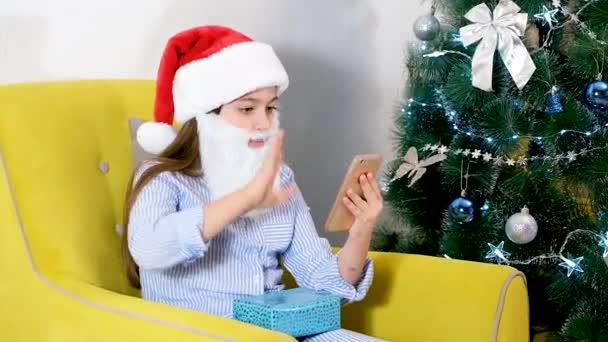 Congratulazioni online per Natale. Ragazza sorridente che utilizza il telefono cellulare per videochiamate. Bambini che parlano di amici e genitori. — Video Stock