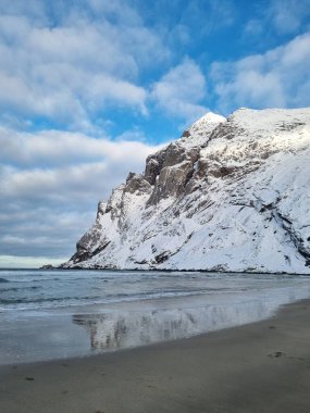 Norveç, Lofoten Adaları 'nda kışın deniz ve dağlarla muhteşem kumlu Bunes plajı manzarası