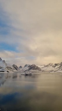 Norveç, Arktik, İskandinavya, Avrupa 'nın kışın Lofoten Gölü' ndeki güzel kar dağları ve altın gökyüzü manzarasını yansıtmaktadır.. 