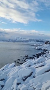 Reine Köyü, Lofoten Adası, Kış zamanı, Sahilde kar örtüsü ve arkasında dağlar.