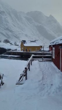 Fiyort kıyısında kışın yoğun kar yağışı olan geleneksel kırmızı rorbu evi. Lofoten Adaları, Norveç